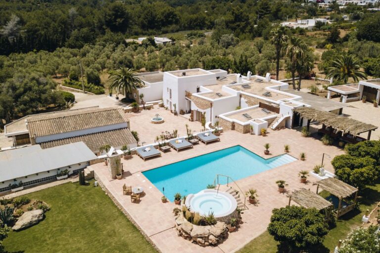 Aerial view white villa with pool, jacuzzi, palm trees, green lawn, paving at Casa Nora, luxury villa rental in Santa Eulalia del Rio, Ibiza
