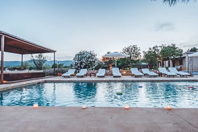 Pool terrace with sunloungers, mountain background, pergola, pink floats at Casa Sage in Santa Eulalia, Ibiza