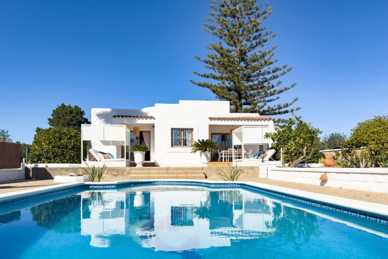 Exterior, white villa, pool and palm trees against blue sky at Casa Solies, Puig d'en Valls, Ibiza