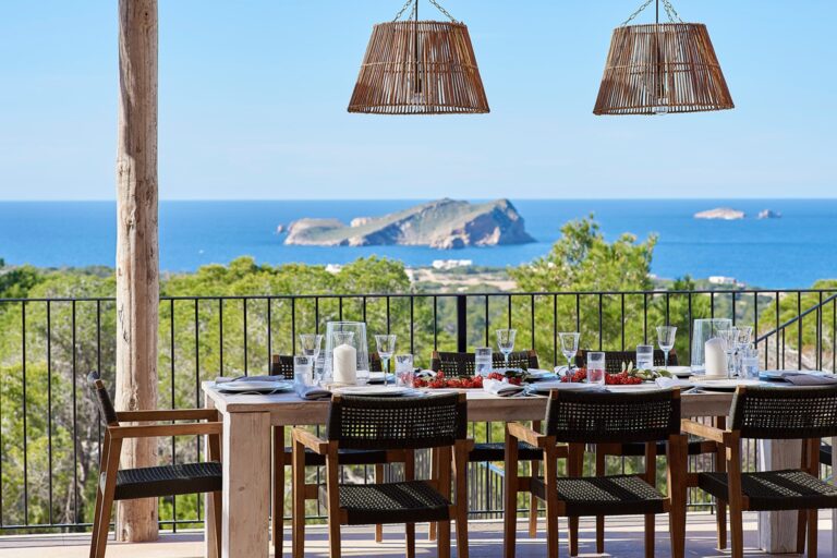 Dining terrace, table set for meal with wooden pergola and island view at Pinos Estate, a luxury villa in Sam Josep, Ibiza