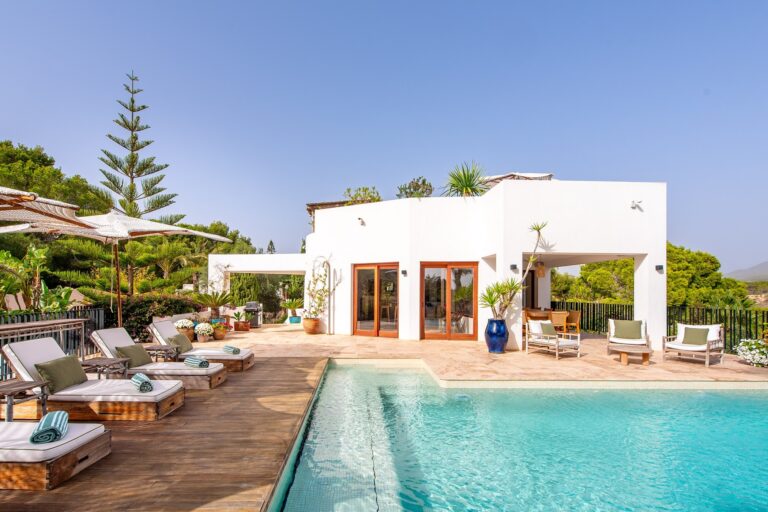Terrace, dining table with wooden chairs and palm tree shade at Porroig Serenity in San Josep, Ibiza