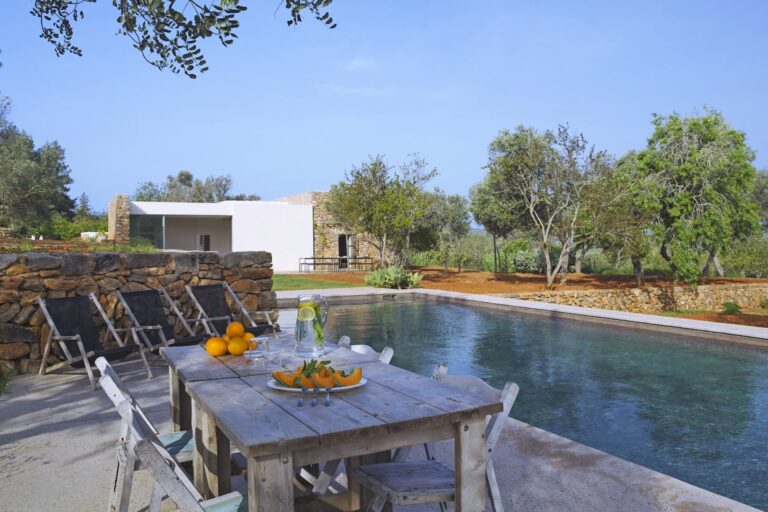 Pool terrace with lounge chairs, wood table and villa at Serene Finca, Santa Eulalia del Rio, Ibiza
