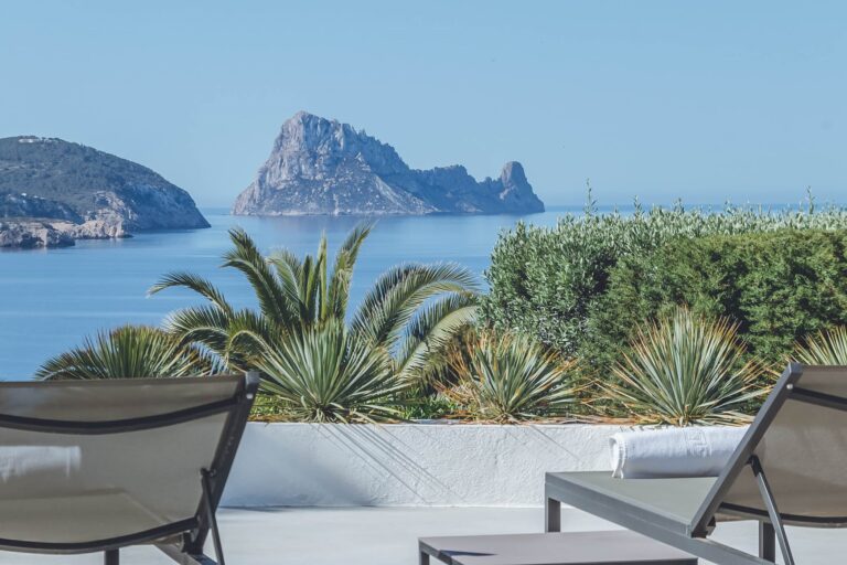 Living room, blue sofas with pool and landscape at Villa Haven, villa to rent in Cala Conta, Ibiza