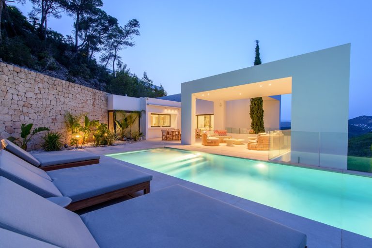 Exterior, infinity pool with loungers, modern terrace, glass pavilion at dusk at Infinity Retreat, Roca Llisa, Ibiza