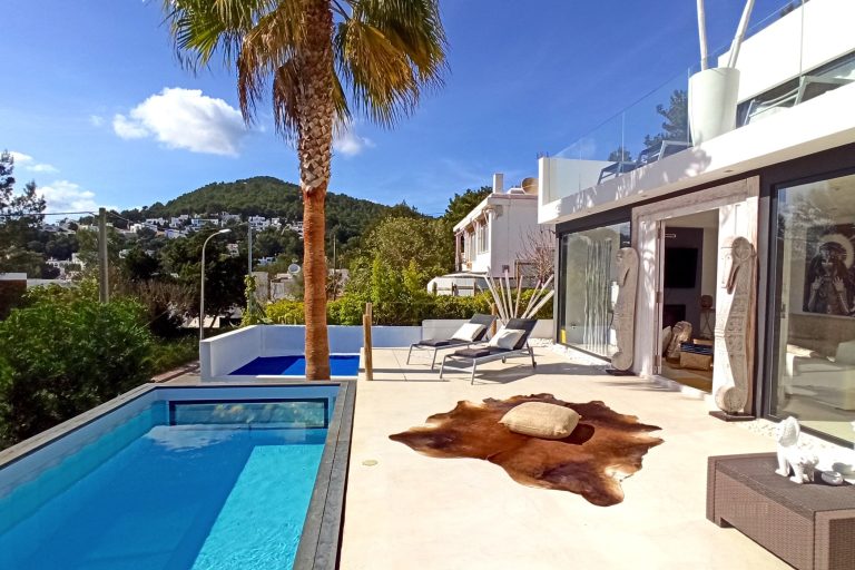 Padel court, green surface with glass enclosure and landscape at Vidal Residence, luxury villa rental in Cala Llonga, Ibiza