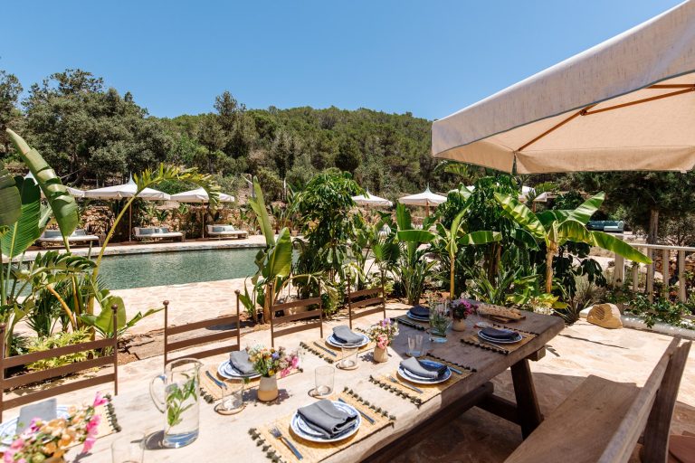 Dining table with colorful place settings, umbrellas and countryside beyond at Villa Utopia in San Lorenzo, Ibiza